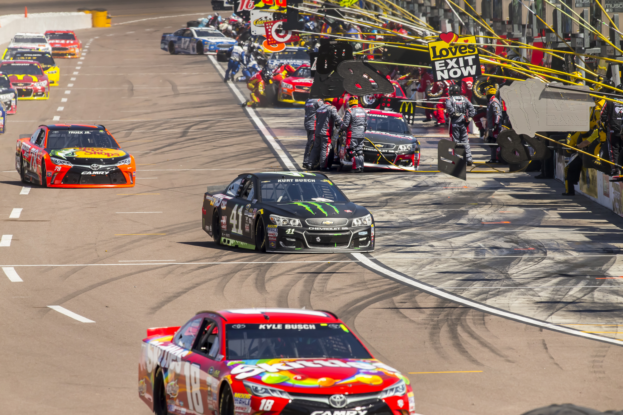 NASCAR drivers entering and exiting pit lane.